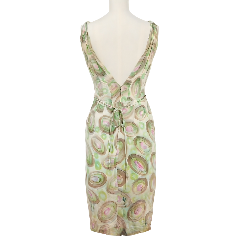 A Sleeveless Jean Louis Designer Dress With A Deep V Back, Pastel Green And Pink Circular Pattern, And A Tie At The Waist, Displayed On A Mannequin—echoing Timeless Hollywood Heritage.