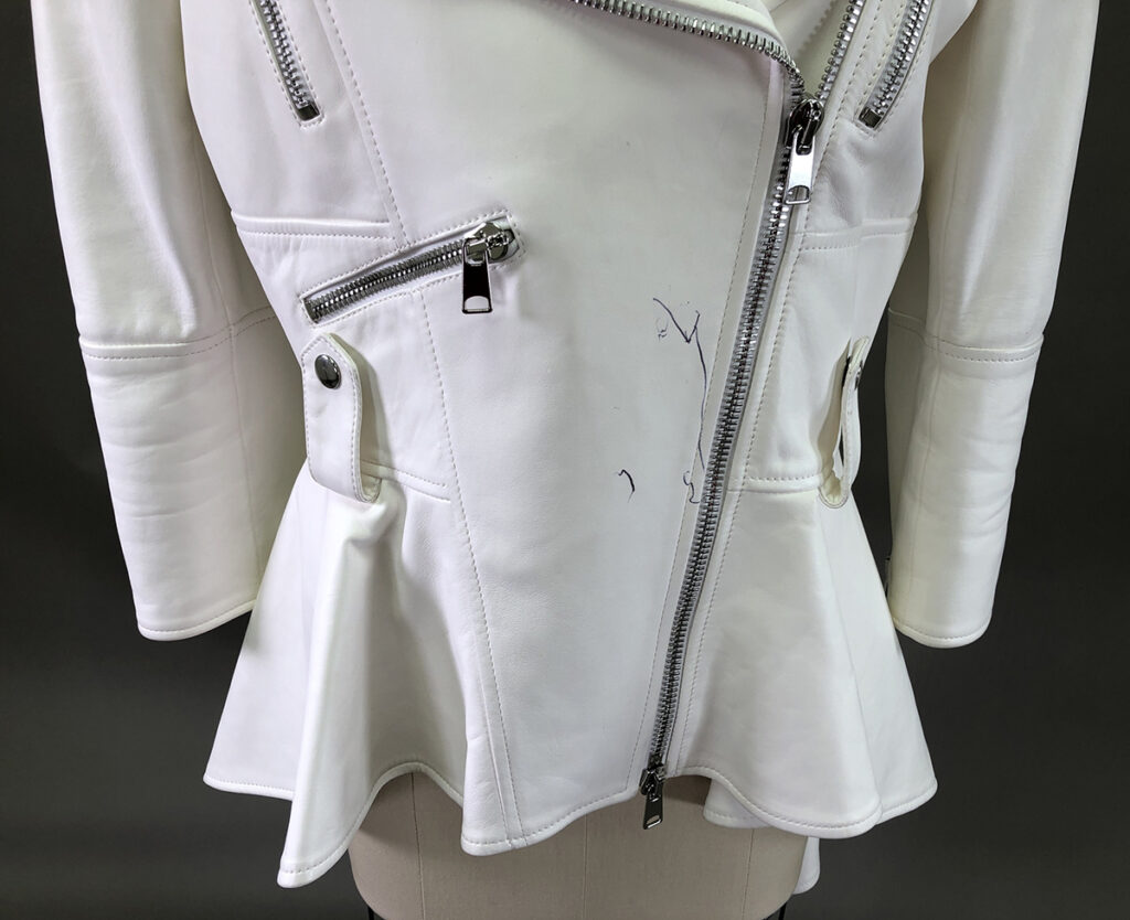 A White Leather Jacket With Silver Zippers And Snap Buttons, Featuring Visible Blue Ink Marks On The Front—perfect For Those Seeking Professional Leather Cleaning Or Expert Leather Care.