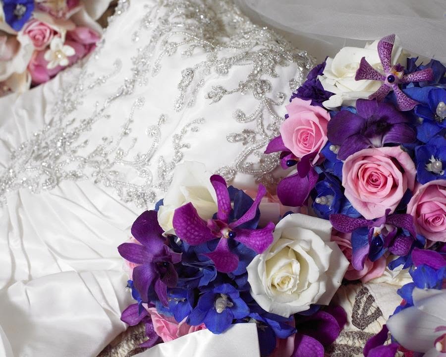Beaded white wedding dress beside pink and purple bouquets